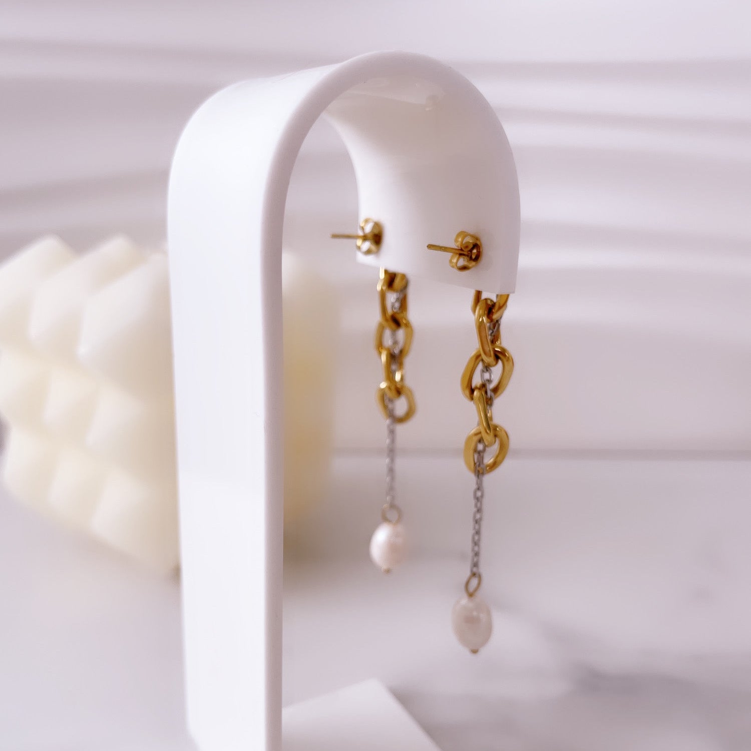 Aretes de perlas Vanytel exhibidos sobre base blanca, joyería elegante.