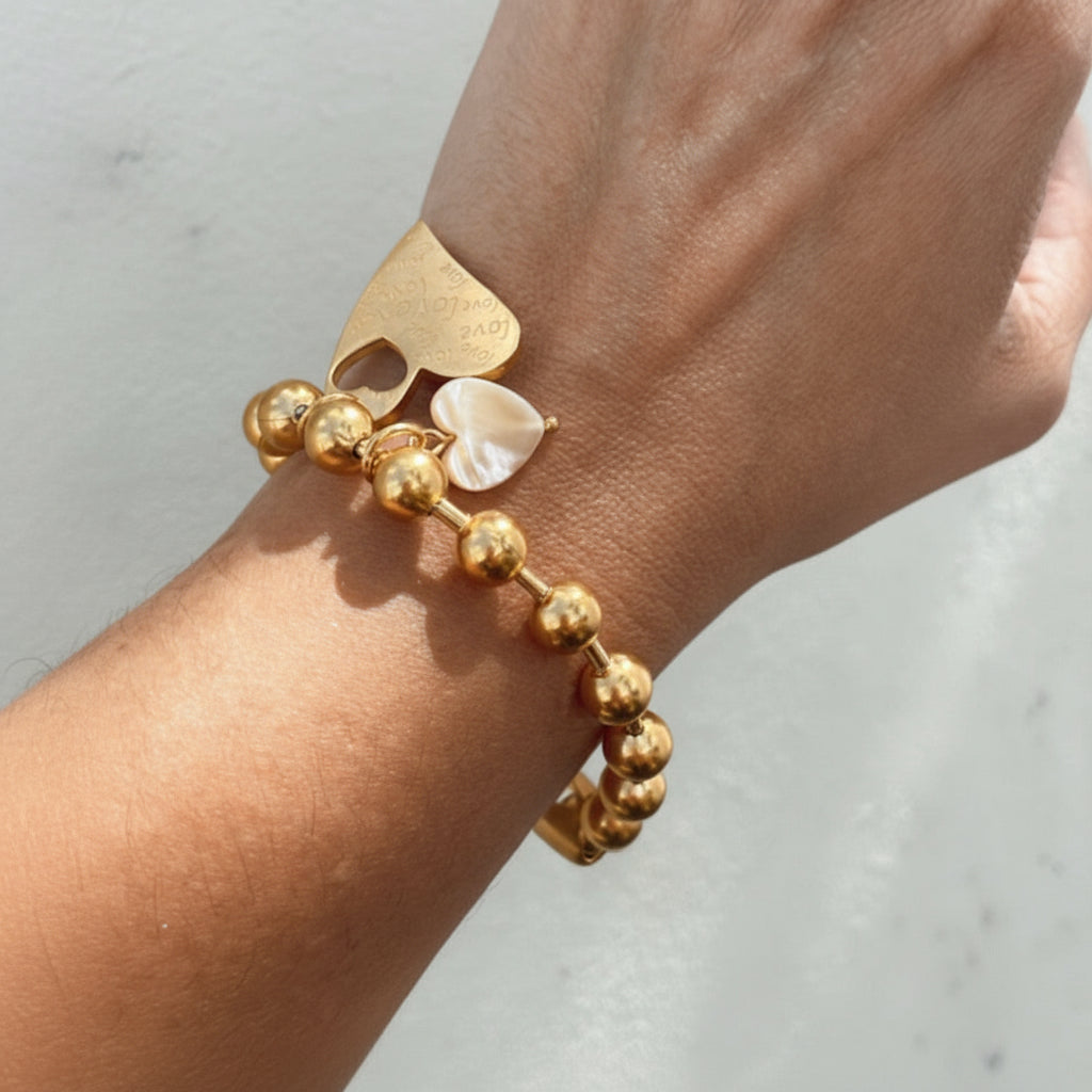 Mujer usando pulsera dorada Lovi con dijes de corazón Vanytel